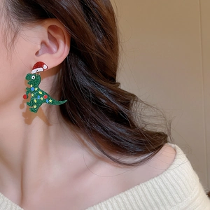 Close-up of green glitter dinosaur earrings with red Santa hats on a model