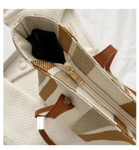 Detail of smooth metal zipper and brown striped woven texture on large tote bag