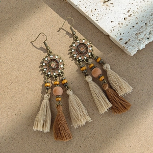 Detail of bohemian sunburst earrings featuring layered silk tassels and wooden beads