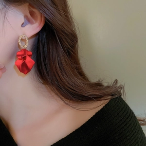 Close-up of elegant red petal drop earring with golden stud on a female model