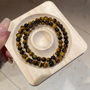 Detailed macro view of tiger eye stone beads bracelet with zircon accents on wood tray