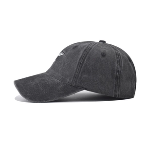 Detailed view of white shark embroidery on washed black cotton baseball cap fabric