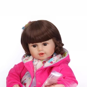 Realistic reborn baby doll with brown hair in a pink hooded jacket on white background