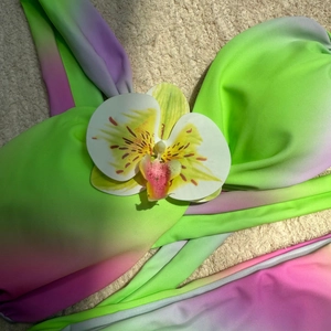 Gros plan d'un haut de bikini dégradé avec une décoration florale d'orchidée blanche