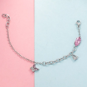 Detail of silver chain bracelet featuring pink butterfly charm and marquise gemstone