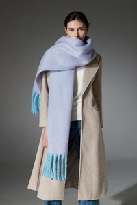 Detail of light purple and blue gradient knit scarf with thick tassels on a model