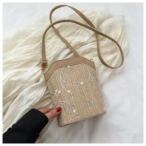 Détail du sac à bandoulière en paille avec broderie florale et garniture en cuir PU brun
