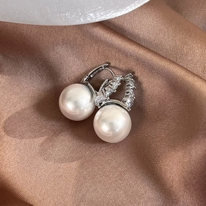 Detailed macro view of French style pearl hoop earrings with crystal accents