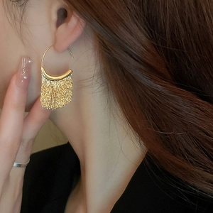 Détail de boucles d'oreilles dorées à pampilles avec chaînes fines et crochet en C