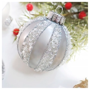 Close-up of silver Christmas ornament ball with glitter stripes and sequins detail