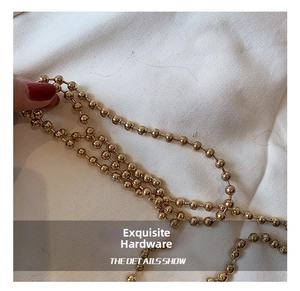 Detail of polished golden ball chain strap for acrylic bags featuring metallic luster