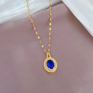 Gros plan d'un collier en acier titane doré avec pendentif gemme bleue et micro-diamants