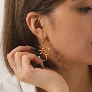 Close-up of model wearing 18K gold stainless steel sun earrings with hammered texture