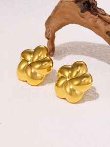 Detailed view of gold flower stud earrings with metallic luster on a textured background