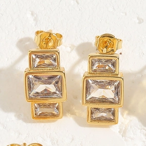 Close-up of gold stud earrings with three rectangular clear cubic zirconia stones