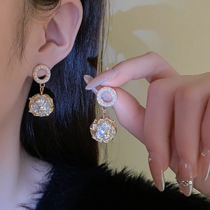 Close-up of elegant gold hollow sphere earrings with pearls worn by a model