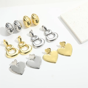 Flat lay of heart and oval textured metal stud earrings in gold and silver finish
