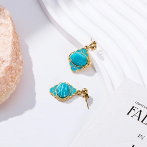 Detailed close-up of vintage gold earrings with blue turquoise stones on decorative props