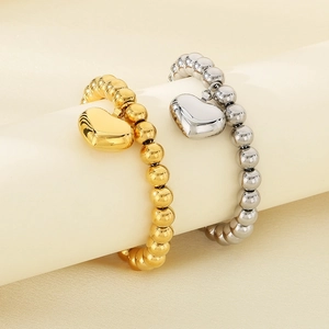 Detailed shot of polished 18K gold and silver beaded bracelets with hollow heart charms