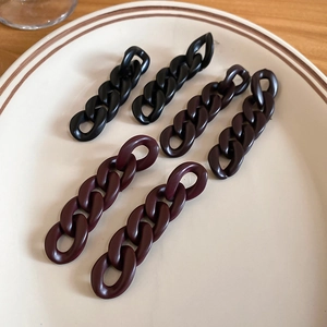 Detail of matte acrylic chain hair clips in black, brown, and burgundy on a ceramic plate
