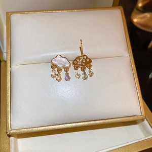 Macro shot of cloud-shaped gold earrings with mother-of-pearl and zircon water drops