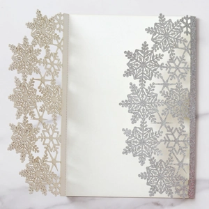 Detail of laser-cut silver glitter snowflake patterns on elegant wedding invitation cards