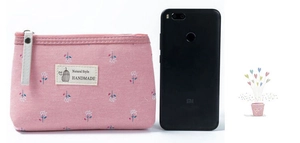 Mini porte-monnaie en toile rose fleurie avec fermeture éclair à côté d'un smartphone