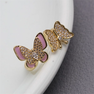 Macro shot of gold butterfly rings with pink enamel and micro-pave zircons on a tray