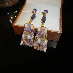 Dettaglio di orecchini in vetro viola con strass a mosaico e base dorata