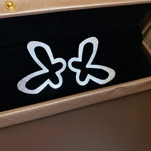 Macro shot of silver butterfly earrings with a matte texture on a dark velvet display