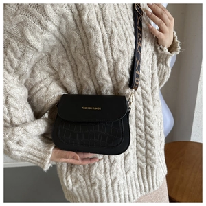 Detail of black faux leather crossbody bag with crocodile pattern and wide strap