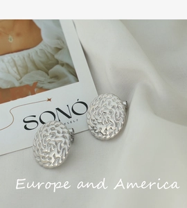 Detailed close-up of silver steel earrings with organic molten texture and relief design