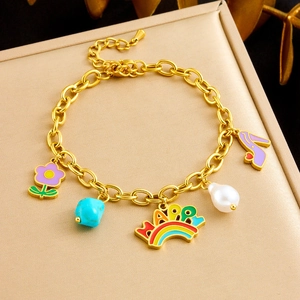 Golden charm bracelet with purple flowers, rainbow happy tag, and pearls on a sleek stand