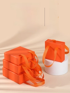 Chic orange drawer-style jewelry gift boxes with matching ribbon handles on pedestals