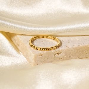 Detailed close-up of a gold stainless steel ring with elegant floral engravings on a silk fabric