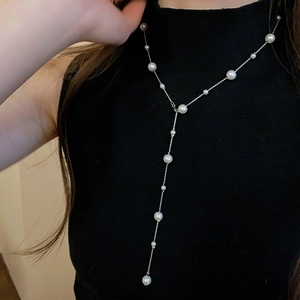 Detail of elegant Y-shaped long pearl necklace showing white pearls on a silver metal chain