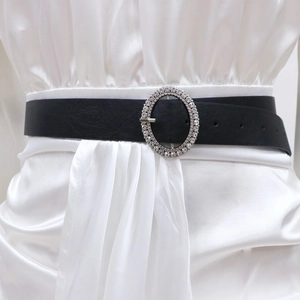 Détail d'une ceinture en similicuir noir avec une boucle ovale ornée de strass brillants