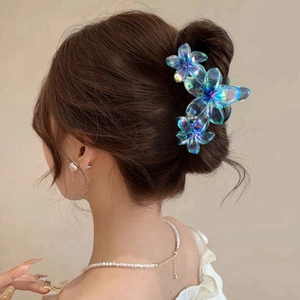 Close-up of a blue and purple gradient flower hair claw clip on a woman's bun hairstyle