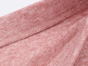 Macro d'un tricot chiné rose montrant les coutures fines et la texture douce