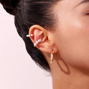 Detail view of 18K gold plated pearl hoop earrings and ear cuffs on a model ear