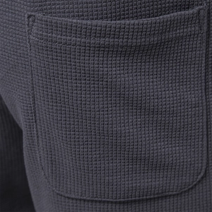 Close-up of the waffle knit fabric and reinforced pocket stitching on dark grey shorts