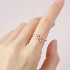 Detailed close-up showing two minimalist rose gold rings with colorful gems on a hand