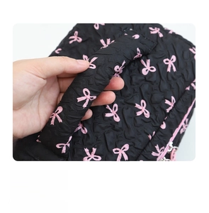 Close-up of the reinforced wide top handle on black quilted bow cosmetic storage bag