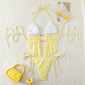 Detail of yellow halter swimsuit featuring textured fabric, waist cutout and wood bead charm