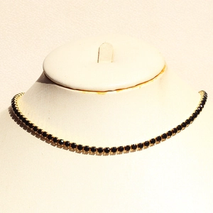 Detail of a minimalist gold-plated tennis chain featuring round black zircon gemstones