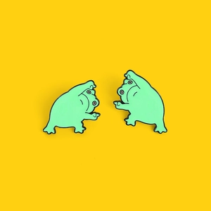 Détail de deux épinglettes en émail grenouille verte amusantes sur fond jaune vif