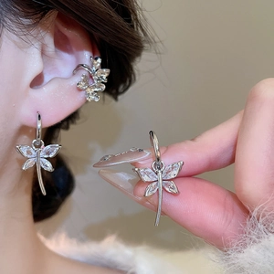 Macro detail of silver butterfly earring and flower ear cuff set with clear crystals