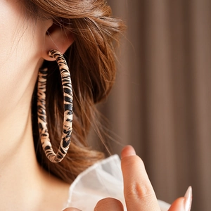 Close-up of a large leopard print hoop earring with retro brown leather texture on model