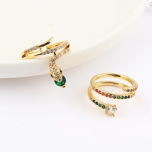 Detail of gold snake ring and colorful zircon spiral ring on a white ceramic tray