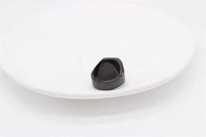Top angle view of a wide black titanium signet ring on a white round display tray